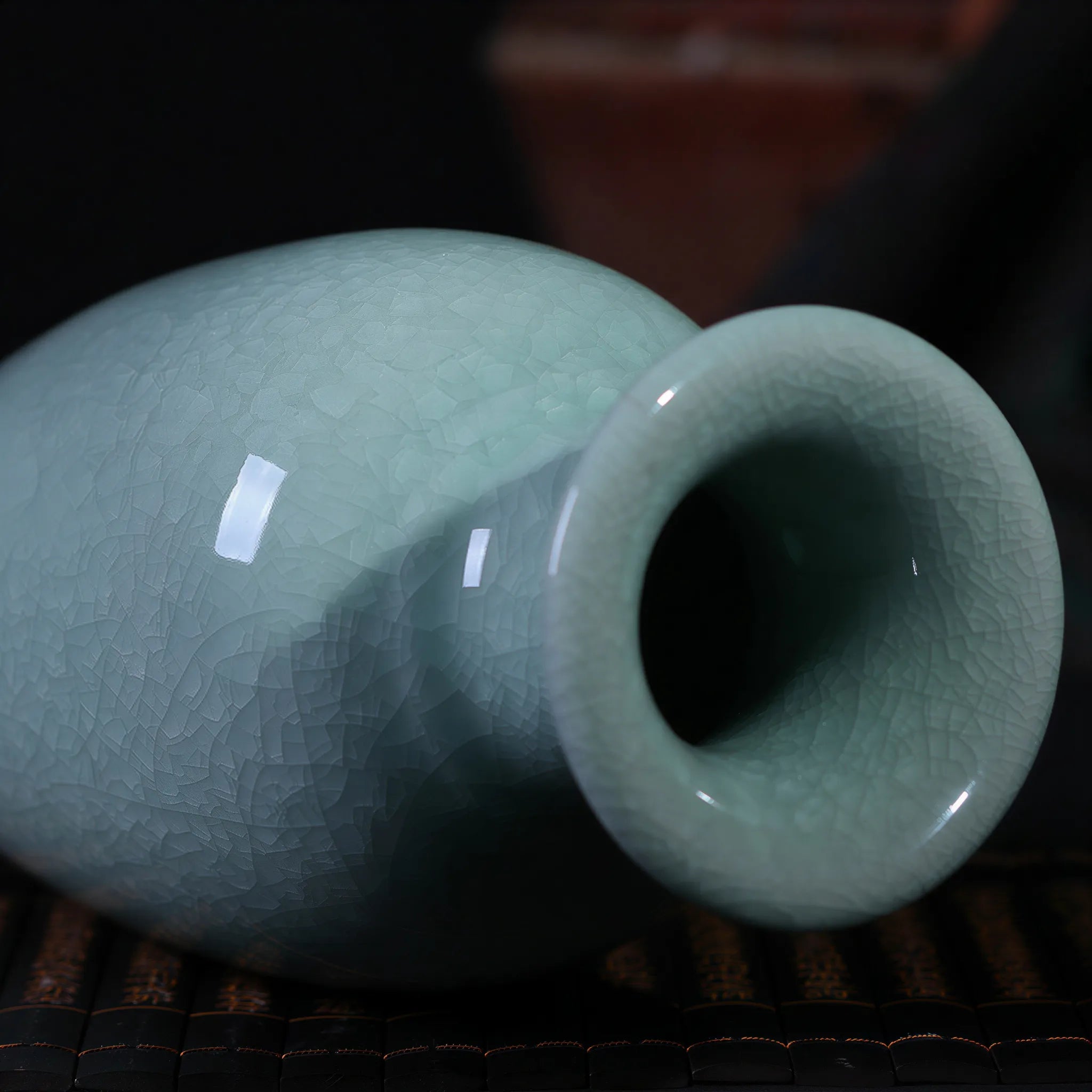 Side profile of the pale celadon Guanyin vase on a bamboo mat