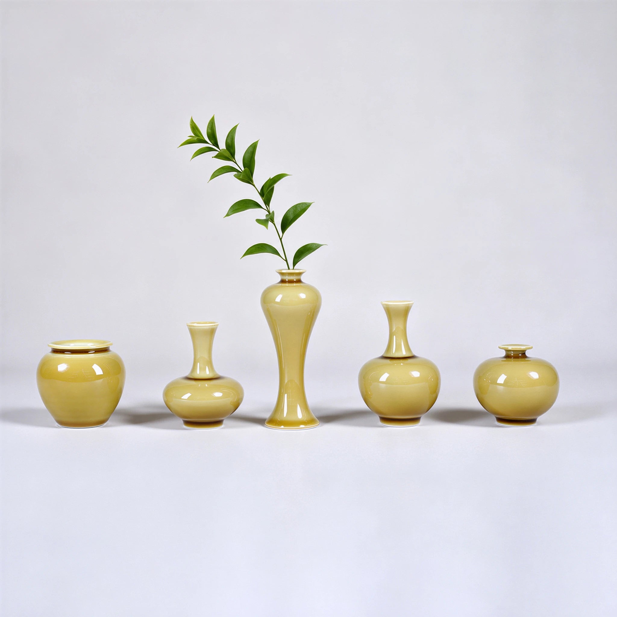 Five small luminous yellow Jingdezhen porcelain bud vases with one green branch