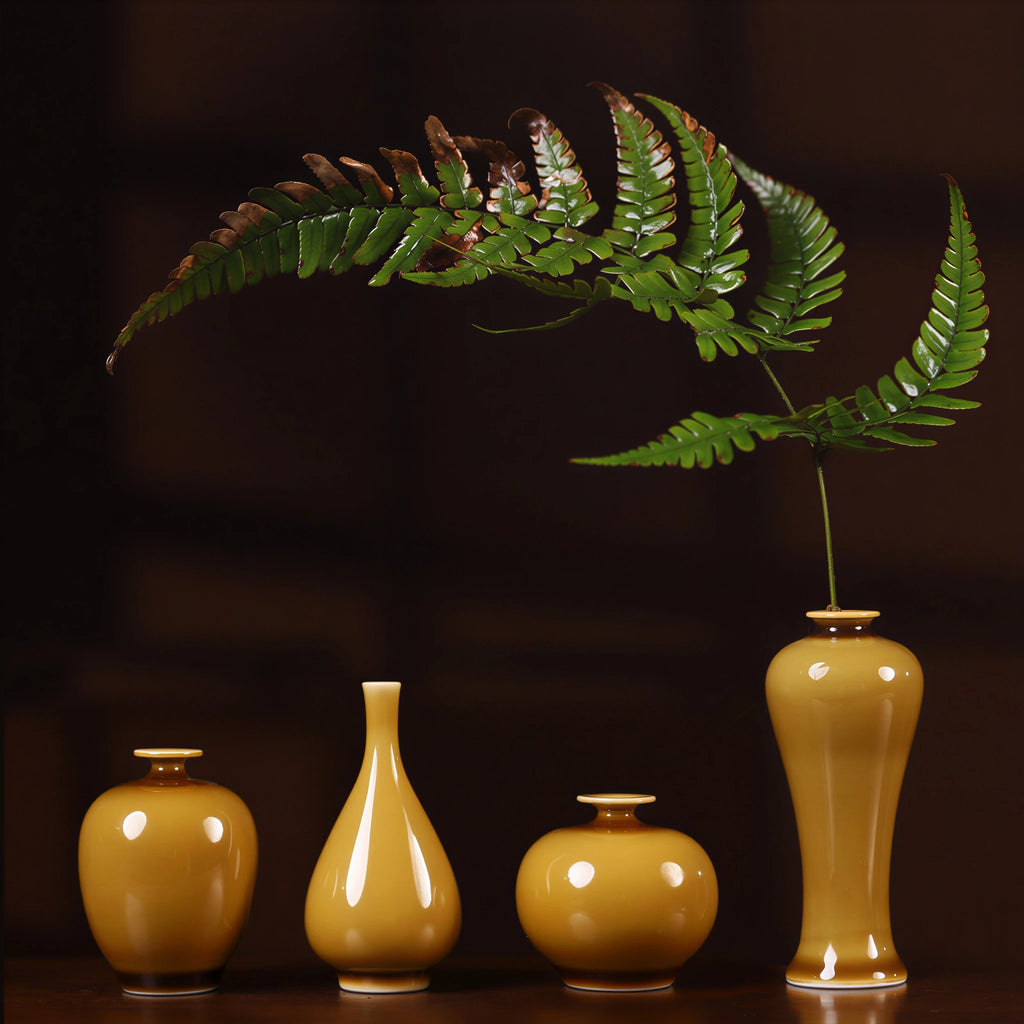 Small luminous yellow porcelain bud vases arranged on a dark wood display surface