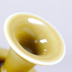 Close detail of a glossy luminous yellow porcelain vase mouth with white rim