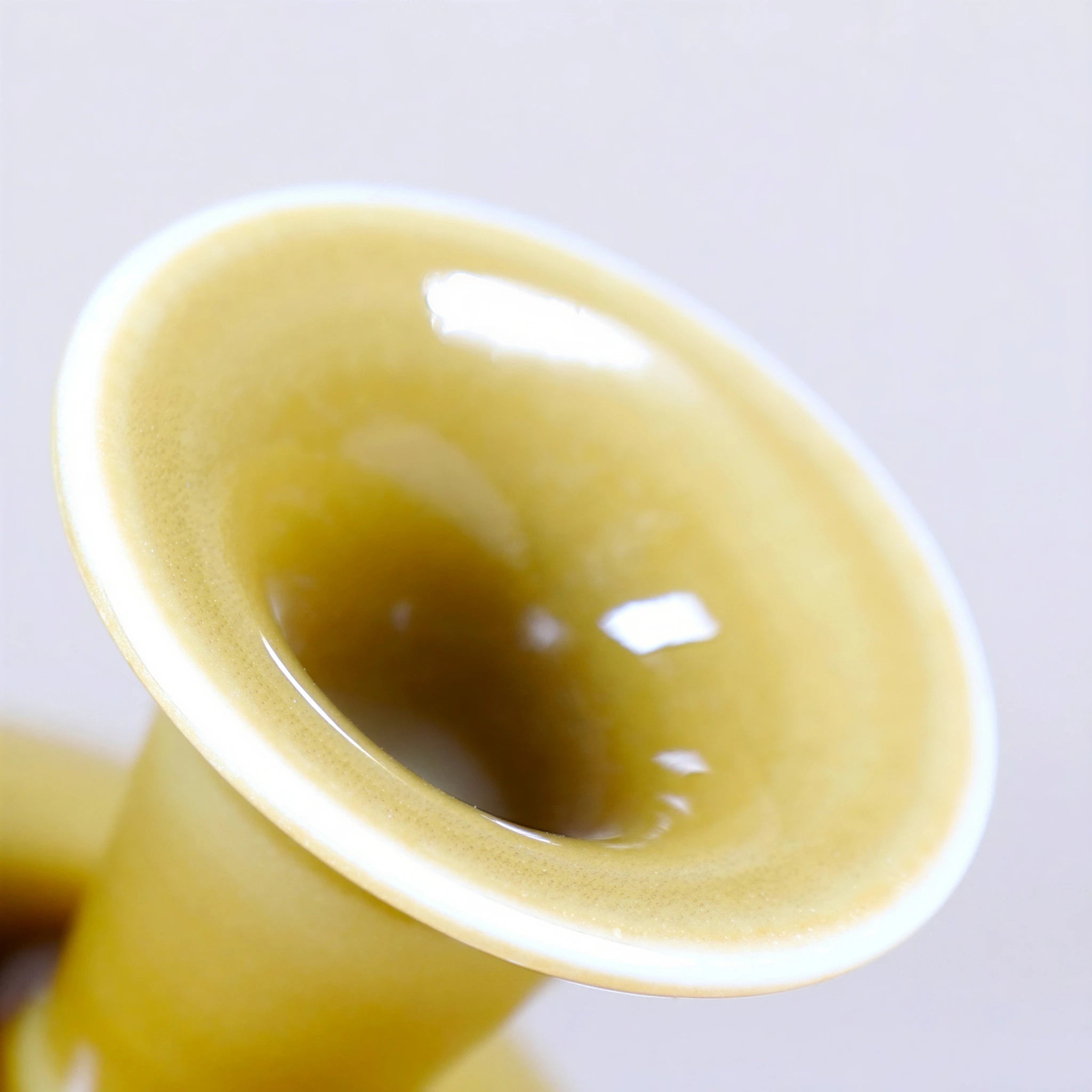 Close detail of a glossy luminous yellow porcelain vase mouth with white rim