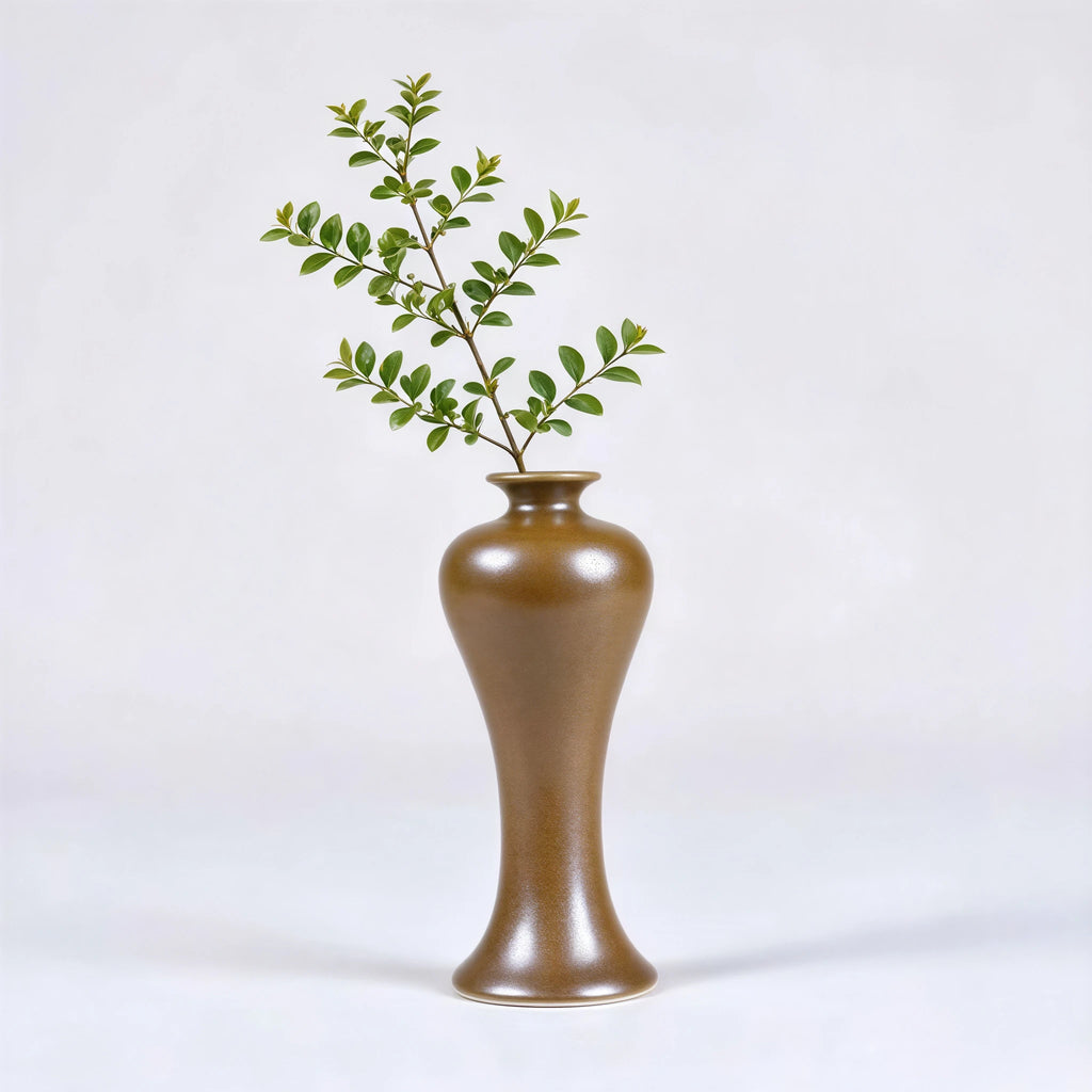 Tall high-shouldered maple-yellow porcelain vase holding a leafy stem.