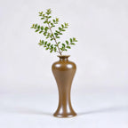 Tall high-shouldered maple-yellow porcelain vase holding a leafy stem.