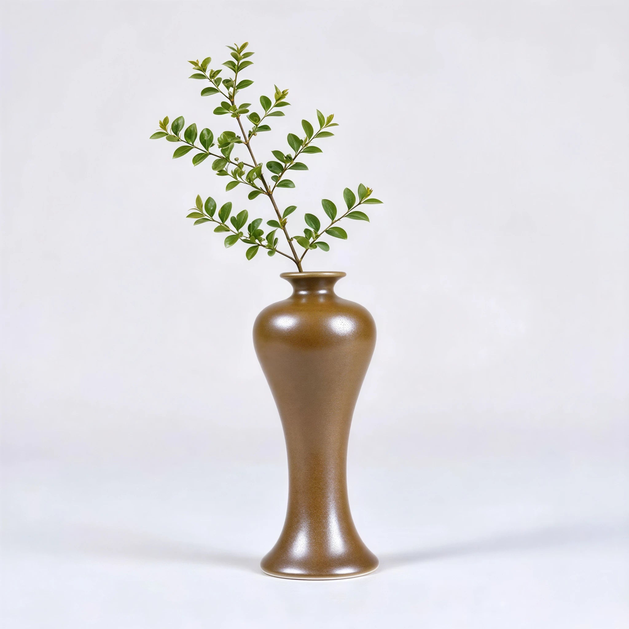 Tall high-shouldered maple-yellow porcelain vase holding a leafy stem.