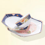Courtyard in Bloom rice bowl resting across navy and blush-pink faceted porcelain plates.