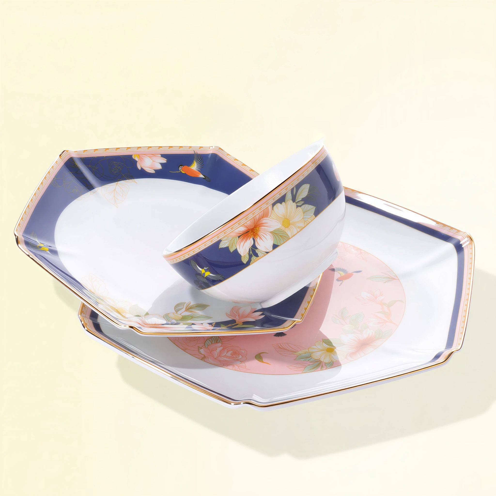 Courtyard in Bloom rice bowl resting across navy and blush-pink faceted porcelain plates.