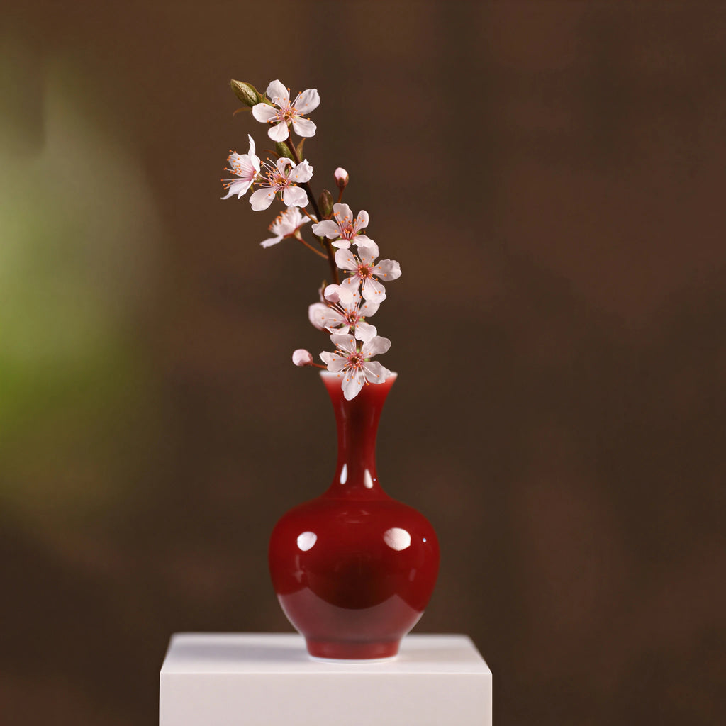 Oxblood red mini vase holding a small flowering branch