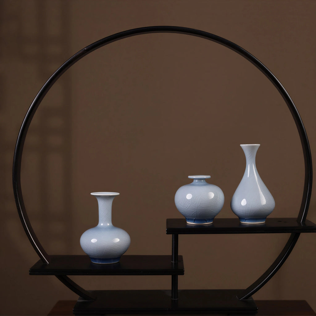 Three pale-blue crackle-glaze porcelain vases on a circular display stand.