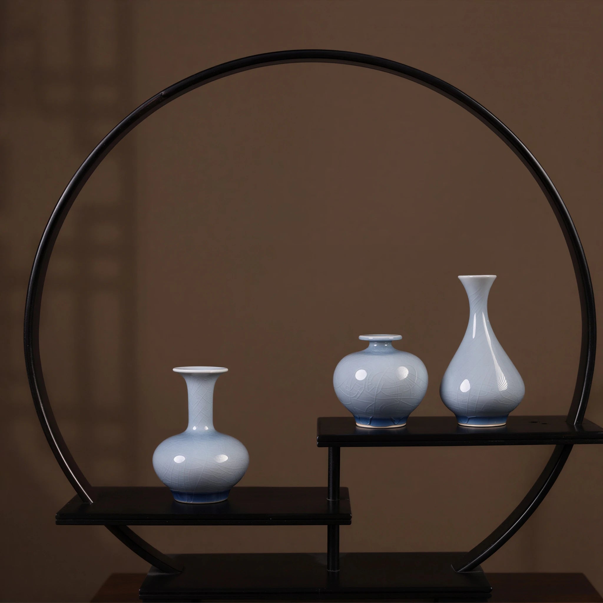 Three pale-blue crackle-glaze porcelain vases on a circular display stand.