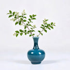 Peacock green mini vase holding a small branch cutting