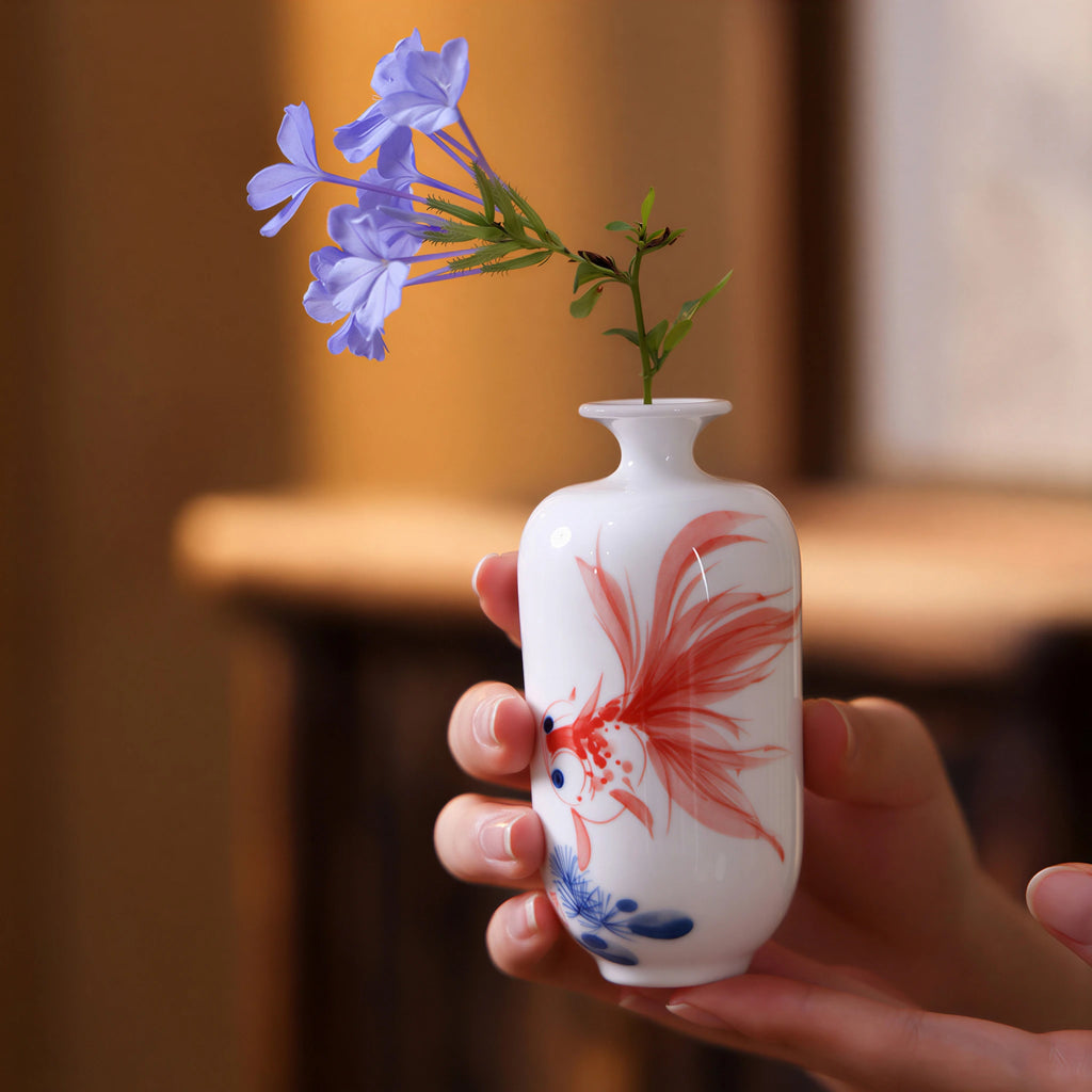  Hand holding a petite Jingdezhen goldfish Meiren vase with a small flower stem