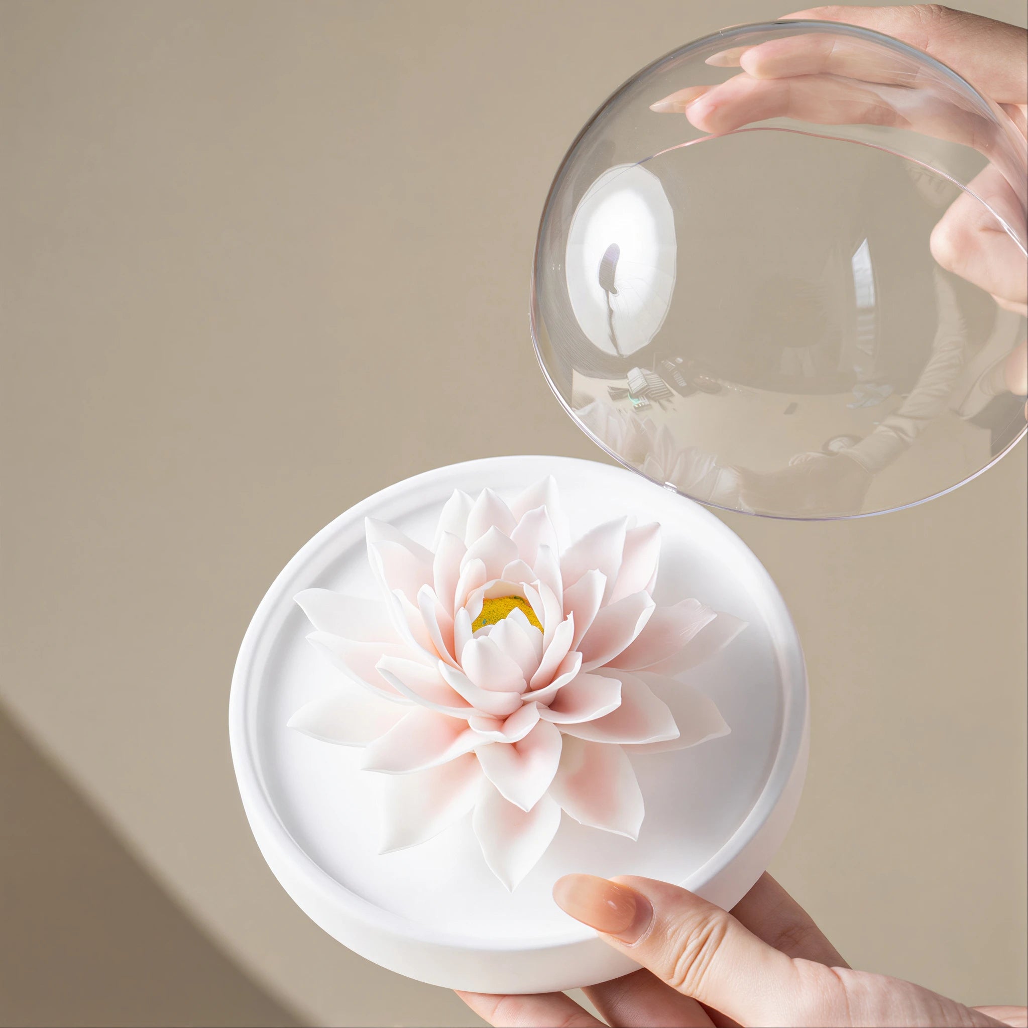 Clear acrylic dome being placed over the porcelain lotus