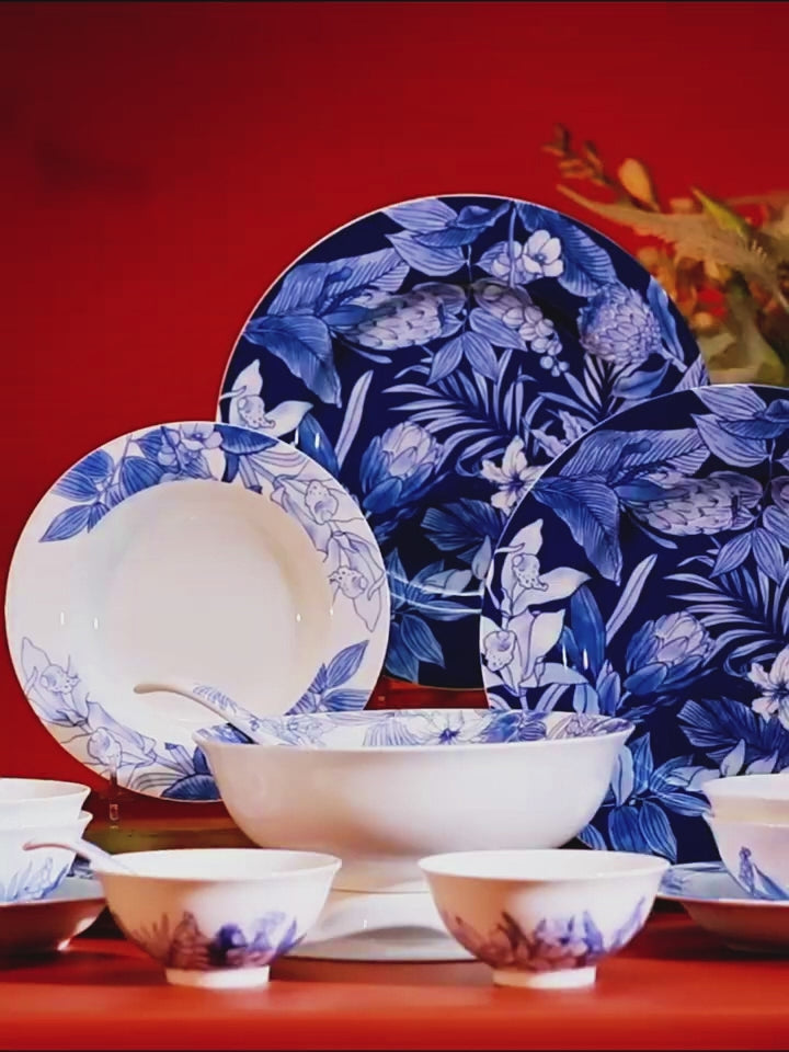 Deep Forest porcelain dinnerware set shown in close-up, including blue botanical plates, bowls, and porcelain spoons.