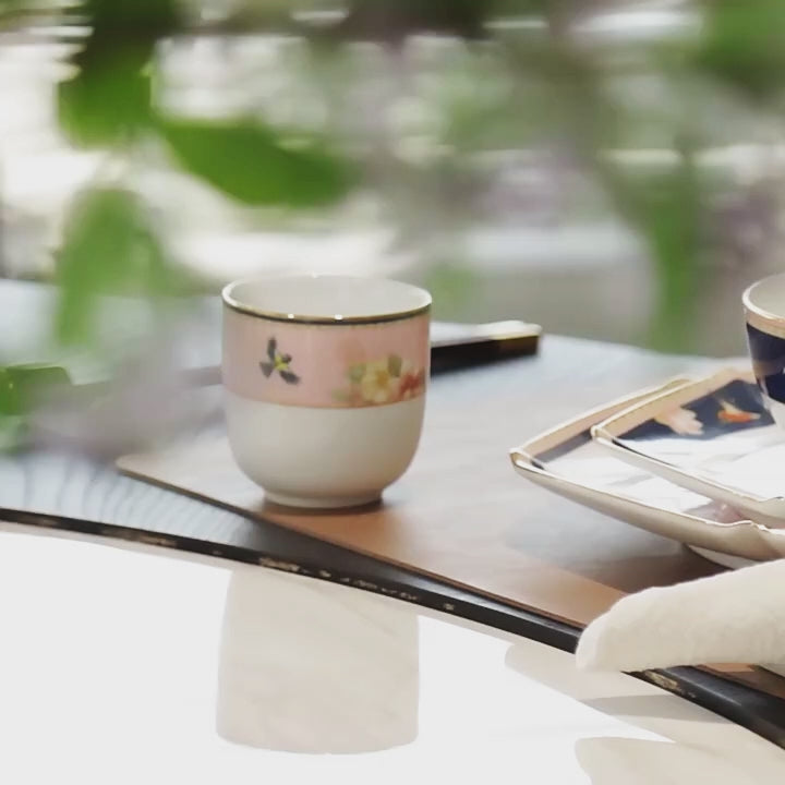 Close product video of the Jingdezhen Courtyard in Bloom eight-piece porcelain setting, showing its faceted forms, floral birds, navy and blush fields, and gold-colored trim.