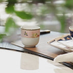 Close product video of the Jingdezhen Courtyard in Bloom eight-piece porcelain setting, showing its faceted forms, floral birds, navy and blush fields, and gold-colored trim.