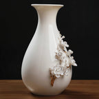 Close view of raised plum blossoms and gold-toned branches on white porcelain