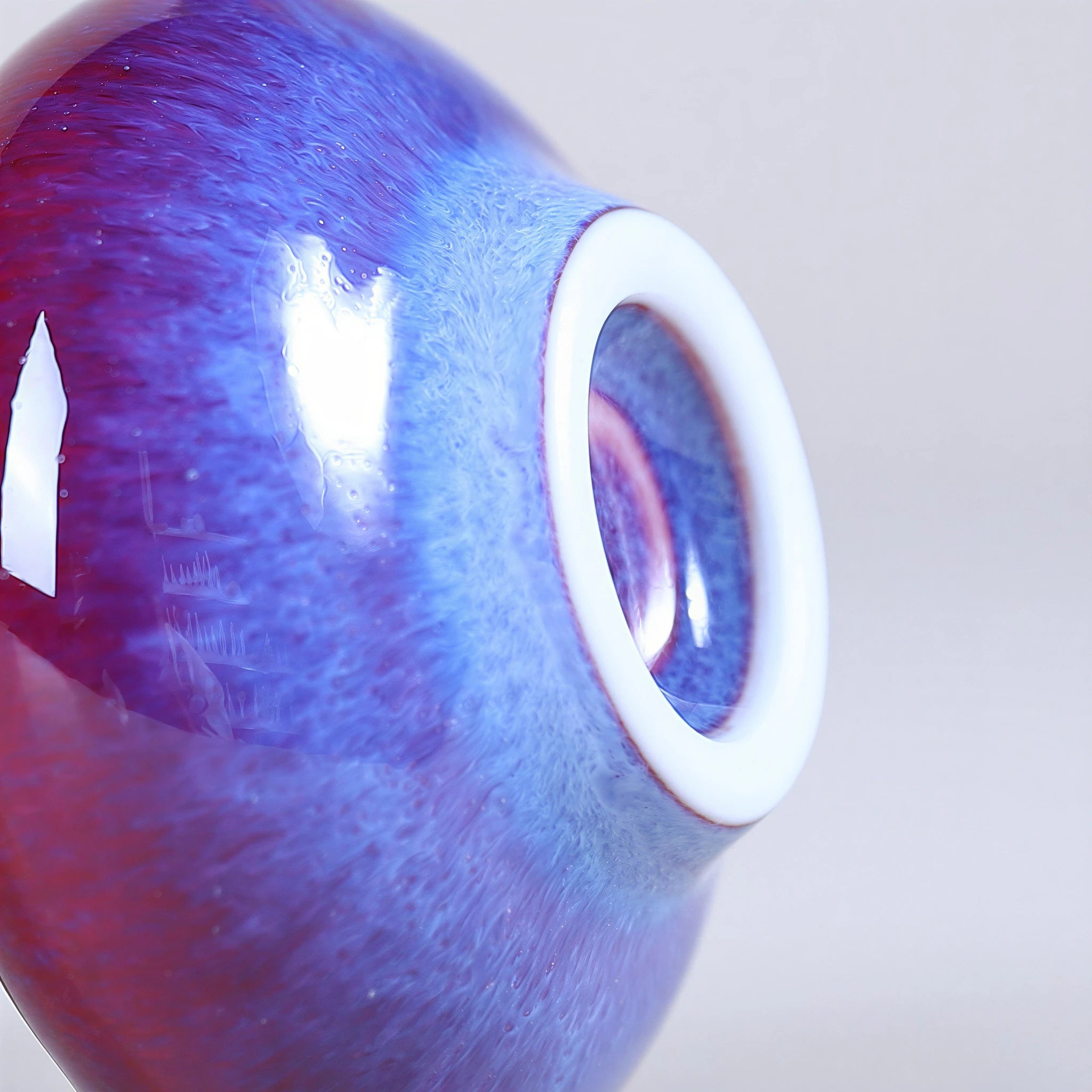 Close view of the blue glaze transition and white foot ring on a rose-purple vase.