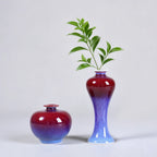 Two rose-purple porcelain vases shown with a fresh green branch.