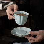 Ru-style celadon coffee cup and scalloped saucer held in hand