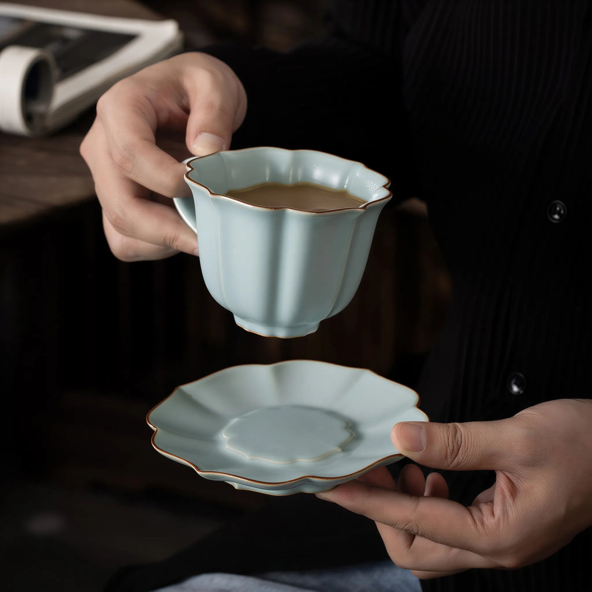 Ru-style celadon coffee cup and scalloped saucer held in hand