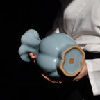 Underside of the Haitang vase held in two hands, showing the lobed foot and a square mark at the center.