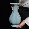 Sky-blue Ru ware Haitang vase held upright, showing its lobed body, slender neck and scalloped rim.