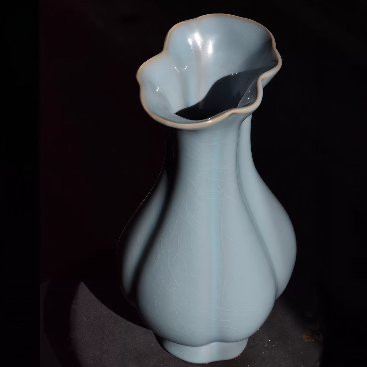 Sky-blue lobed Haitang vase standing on a dark display surface, viewed from above.