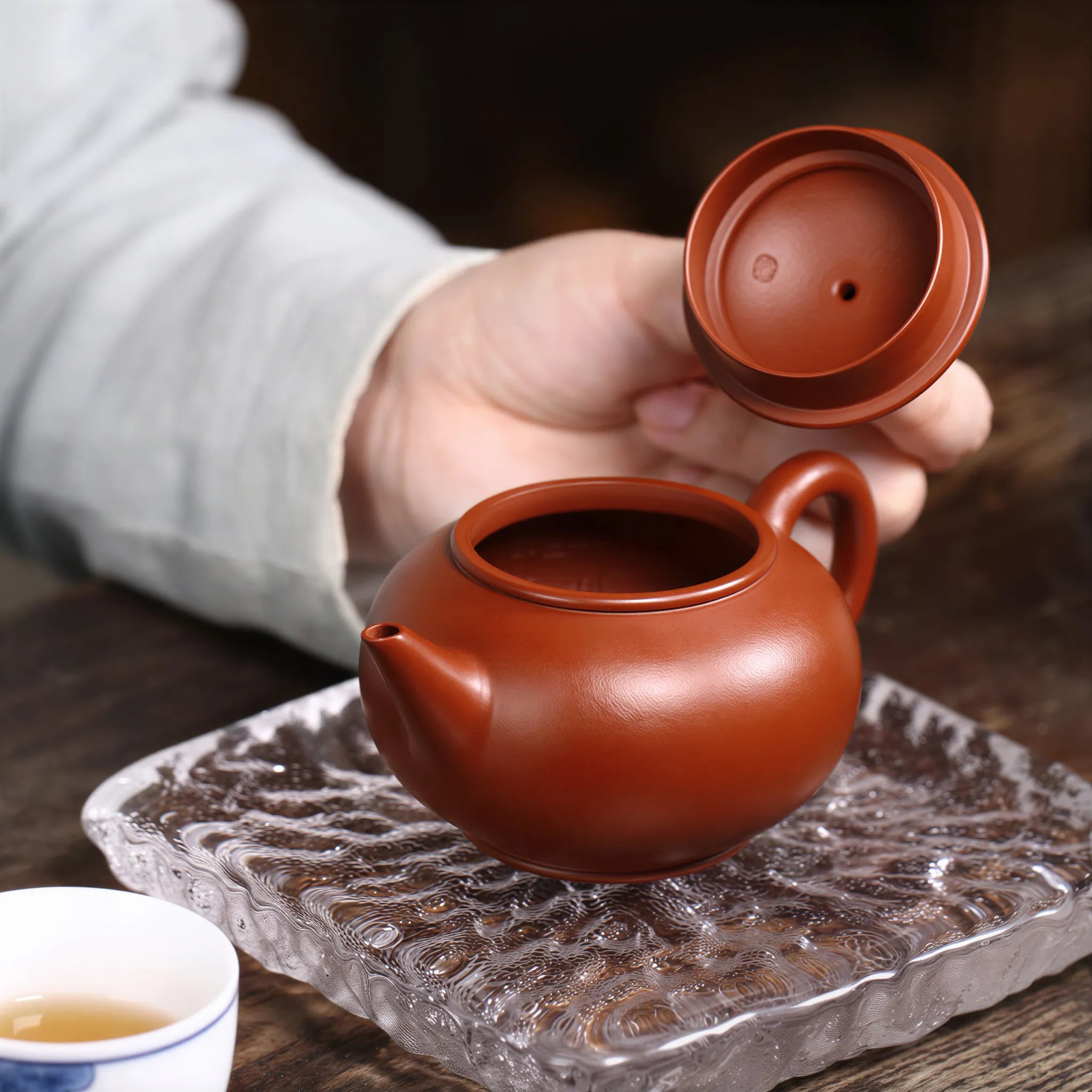 Hand lifting the fitted lid of the Shui Ping teapot