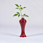 Slender oxblood red porcelain vase with a green stem