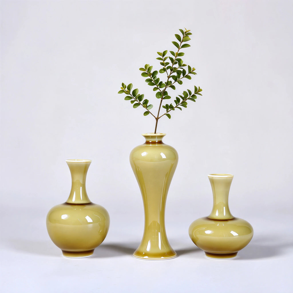 Three small luminous yellow porcelain vases styled with slender green stems