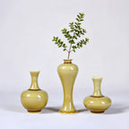 Three small luminous yellow porcelain vases styled with slender green stems