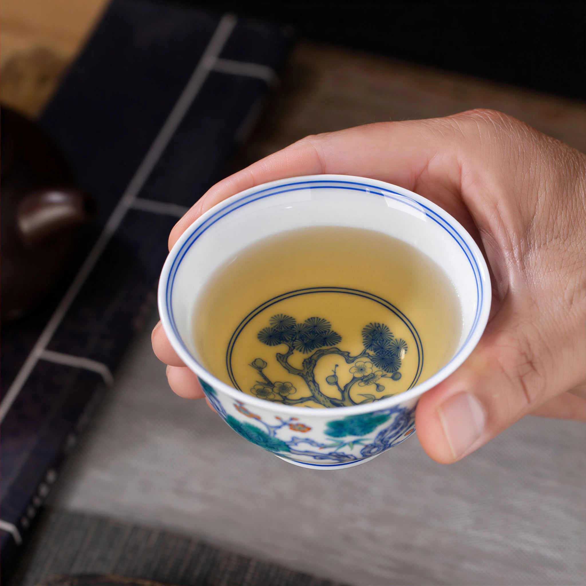 Filled Three Friends teacup held in one hand