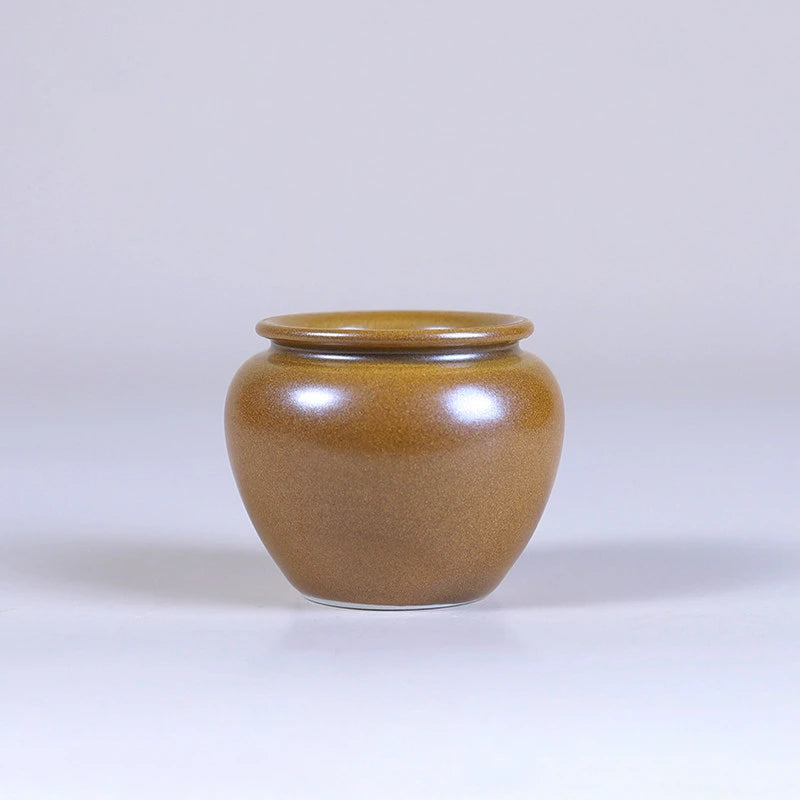 Wide-mouth maple-yellow mini porcelain vase with a rounded body.