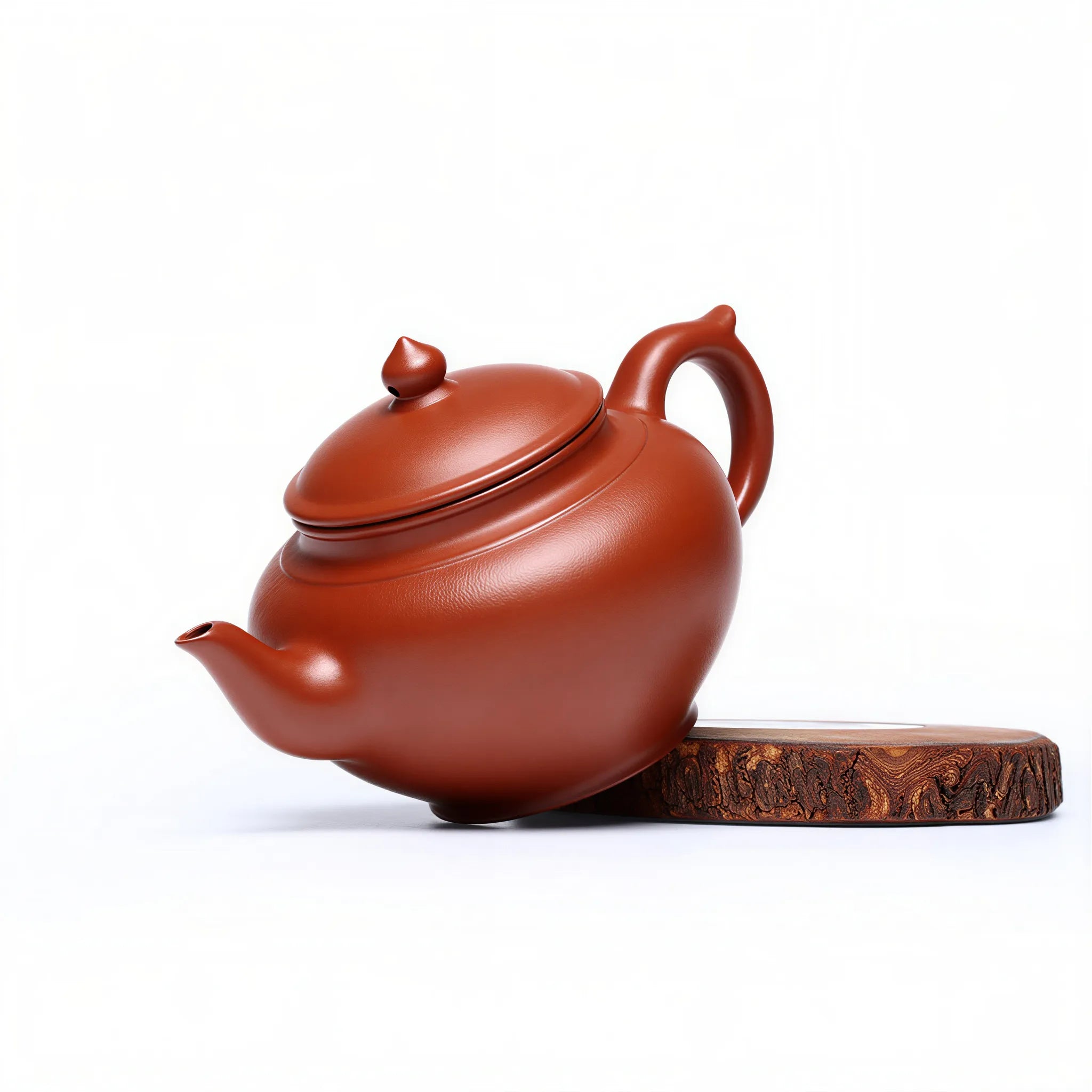 Angled view of the rounded red zisha body, handle and spout