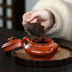 Tea leaves being placed into the low Xu Bian teapot