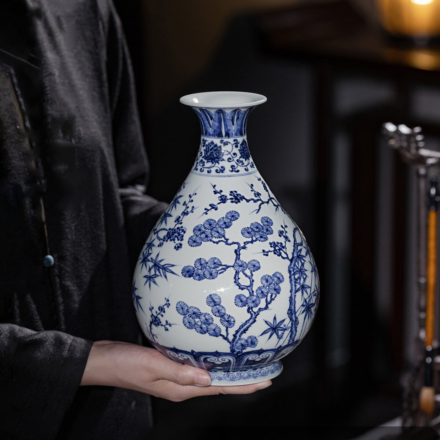 Handheld scale view of a Xuande-style blue-and-white Yuhuchun vase with pine, bamboo and plum motifs