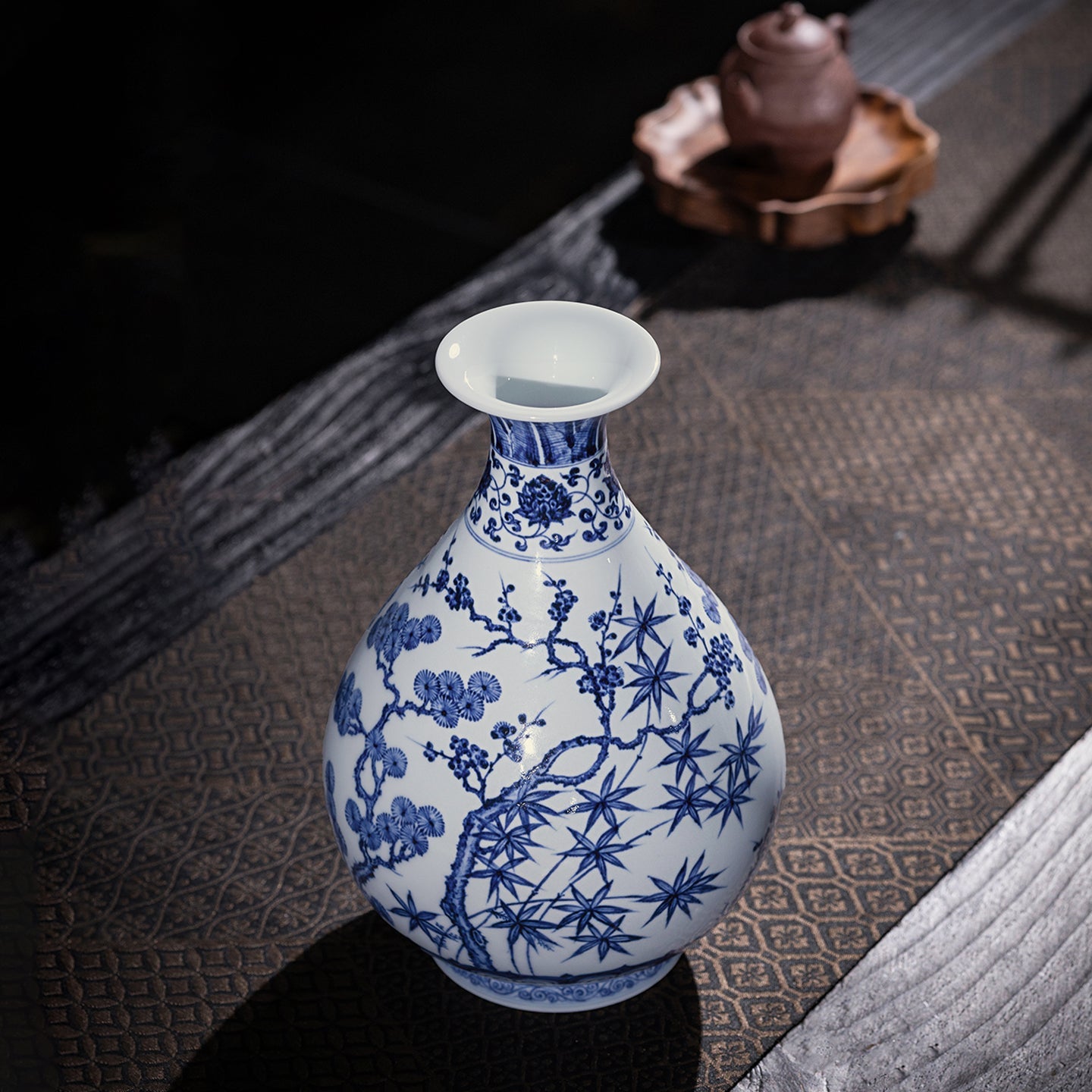 Blue-and-white Yuhuchun vase displayed on a tea table with pine, bamboo and plum decoration