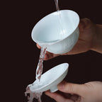Yingqing tasting cup with carved mountain relief during a water rinse